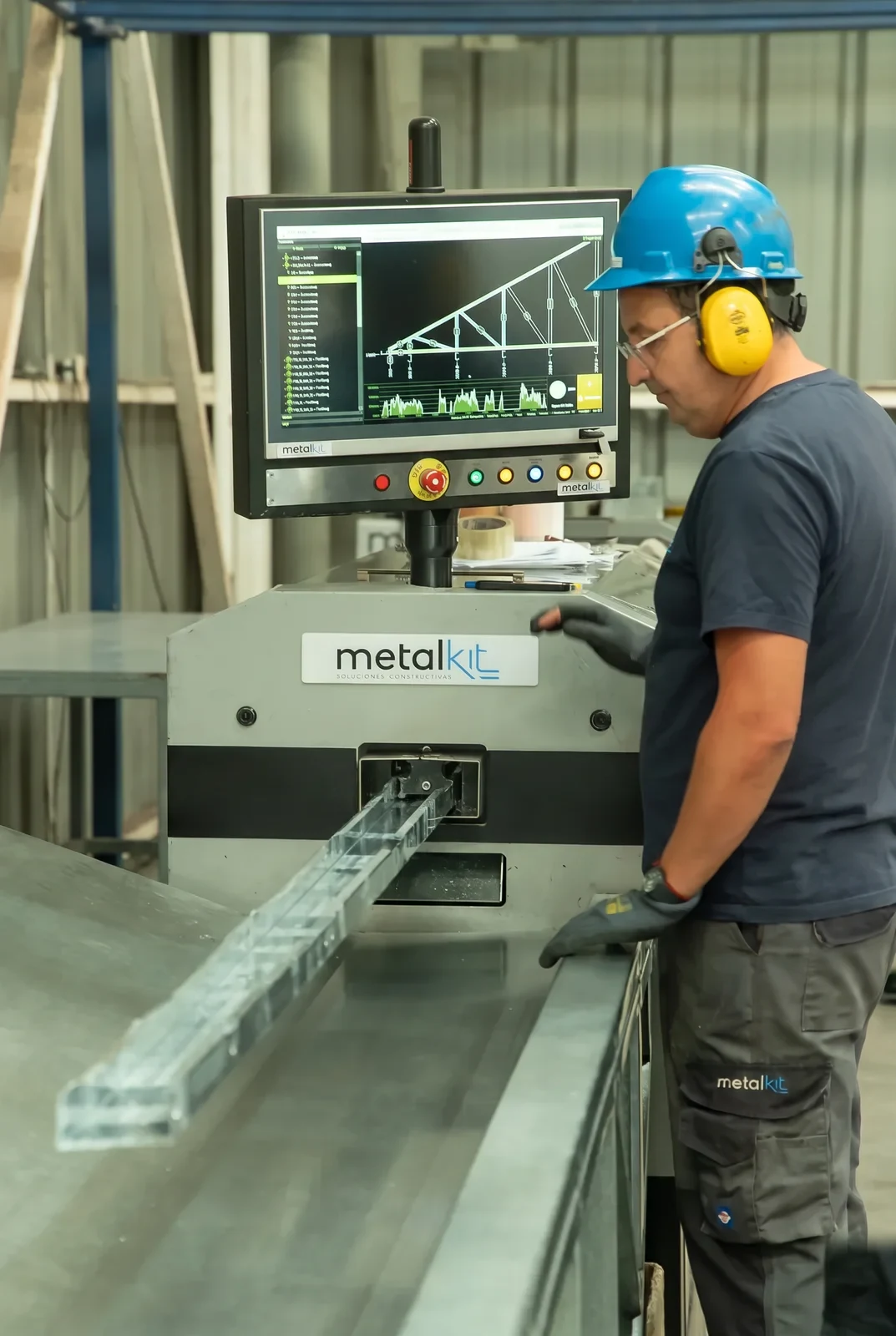 Operario de Metalkit junto a la máquina CNC que corta y rotula los perfiles